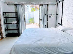 1 dormitorio con 1 cama blanca grande frente a una ventana en Bingin Bienvenue Guest House, en Uluwatu