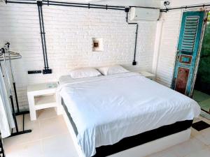 1 dormitorio con cama blanca y pared de ladrillo blanco en Bingin Bienvenue Guest House, en Uluwatu