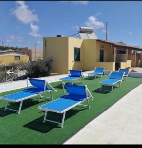 a group of blue lounge chairs sitting on the grass at Appartamenti Da Nicola in Lampedusa