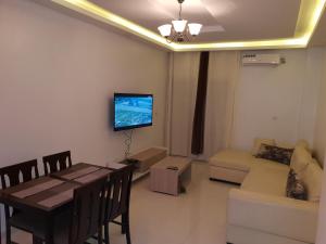ein Wohnzimmer mit einem Tisch und einem TV an der Wand in der Unterkunft Luxueux Appartement F3 in Dakar