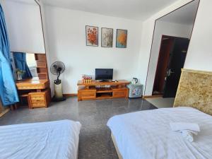 Cette chambre comprend deux lits et un bureau avec une télévision. dans l'établissement Homestay NHÀ THỦY, à Vung Tau