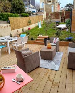 eine Außenterrasse mit einem Tisch und Stühlen sowie einem Tisch und Stühlen in der Unterkunft Maison de vacances familiale à Trouville-sur-mer in Trouville-sur-Mer