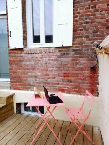 einen rosa Tisch mit einem Laptop neben einem Backsteingebäude in der Unterkunft Maison de vacances familiale à Trouville-sur-mer in Trouville-sur-Mer