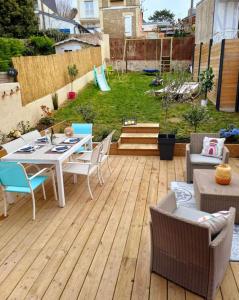 une terrasse en bois avec une table et des chaises. dans l'établissement Maison de vacances familiale à Trouville-sur-mer, à Trouville-sur-Mer