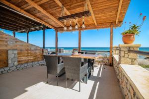 a patio with a table and chairs and the ocean at Pearl of Stegna - Beach House in Archangelos