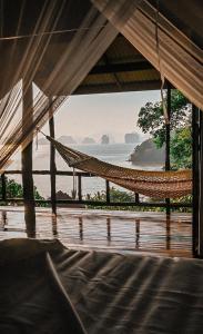 a hammock in a room with a view of the ocean at Hillhouse - Koh Yao Noi in Ko Yao Noi