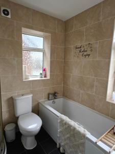 a bathroom with a tub and a toilet and a window at Cornyx House by Arz Stays - Solihull - 6 Beds - NEC BHX airport JLR Resorts World Family Groups Professionals Contractors Free Parking Driveway in Solihull