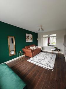 a living room with a brown couch and a green wall at Cornyx House by Arz Stays - Solihull - 6 Beds - NEC BHX airport JLR Resorts World Family Groups Professionals Contractors Free Parking Driveway in Solihull