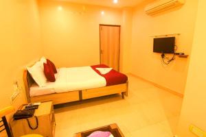 a small bedroom with a bed and a television at Jjs PARK INN in Chennai