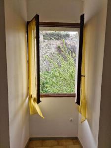 Cette chambre dispose d'une fenêtre avec des rideaux jaunes. dans l'établissement Appartement centre Saint Florent, à Saint-Florent