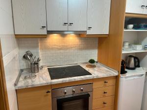 una cucina con mobili bianchi e un forno a piano cottura di Apartamento Terraza Arenales del Sol ad Arenales del Sol