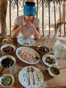 kobieta siedząca przy stole z talerzami jedzenia w obiekcie Glimra eco lodge w mieście Hambegamuwa