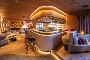 eine Bar in einem Restaurant mit Sofas und Stühlen in der Unterkunft Savoy Dolomites Luxury & Spa Hotel in Wolkenstein in Gröden