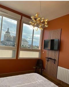 a bedroom with a chandelier and windows and a bed at Hôtel Déco'lia-Soirée étape in Ballon