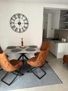 a table and chairs in a kitchen with a clock on the wall at Apartman ANNA ATINA Budva in Budva +9 photos