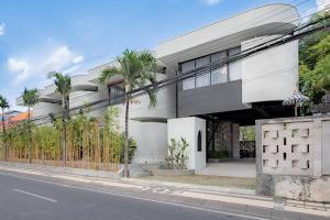 a white building with palm trees in front of a street at The Drupadi Apartments Town House LOLA in Seminyak