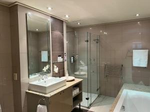 a bathroom with a sink and a shower at Cape Royale Luxury Suite in Cape Town
