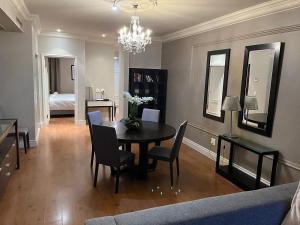 a dining room with a table and chairs and a chandelier at Cape Royale Luxury Suite in Cape Town