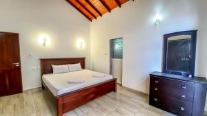 a bedroom with a bed with a dresser and a tv at Newolivevilla in Katunayake