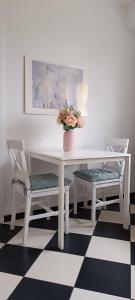 uma mesa branca com duas cadeiras e um vaso com flores em Apartament na Poli em Wałbrzych