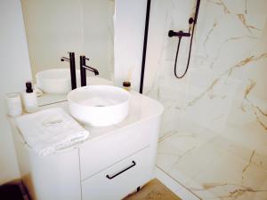a white bathroom with a sink and a shower at Central Apartments Ogarna 5 in Gdańsk