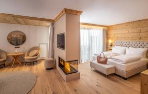 ein Wohnzimmer mit einem Bett und einem Kamin in der Unterkunft Savoy Dolomites Luxury & Spa Hotel in Wolkenstein in Gröden