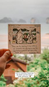 a person holding up a piece of paper with a drawing on it at Hillhouse - Koh Yao Noi in Ko Yao Noi
