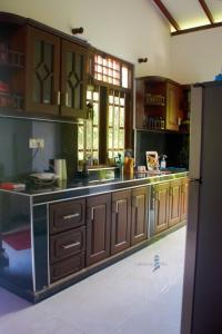 cocina con armarios de madera y encimera en Lighthouse Villa Koggala, en Galle