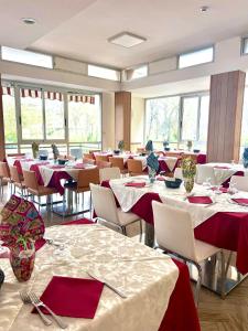 uma sala de jantar com mesas e cadeiras com toalhas de mesa vermelhas em Hotel Naica em Rimini