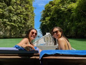 twee vrouwen achterin een boot in het water bij Hillhouse - Koh Yao Noi in Ko Yao Noi