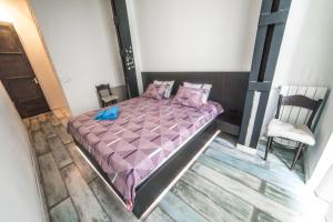 a bedroom with a purple bed and a chair at Loft Style Apartment in Tbilisi City