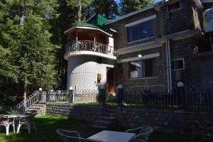 a house with a balcony and a table and chairs at Serenity House in Nathia Gali