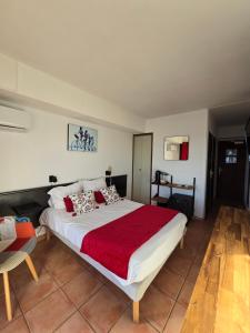 a bedroom with a large bed with a red blanket at Hotel Chanteplage in Saint-Cyr-sur-Mer