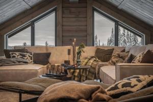 a living room with couches and windows in a cabin at Hyttekos Lodge: luxury ski-in/ski-out chalet in Kvitfjell