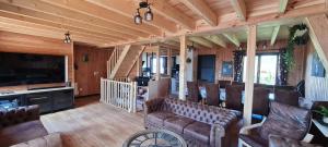 a living room with couches and a large television at Grand Chalet Balnéo Zen Altitud in Chastreix