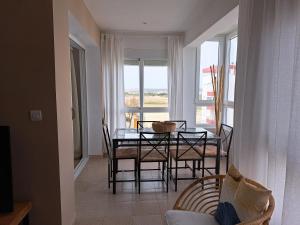 d'une salle à manger avec une table, des chaises et une fenêtre. dans l'établissement Ático primera línea de playa con vistas al mar-Climatizado-Wifi-Parking, à El Puerto de Santa María