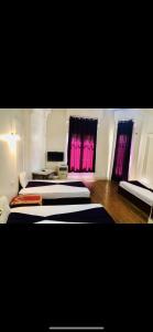 2 Betten in einem Zimmer mit rosa Vorhängen in der Unterkunft Oh ! Cairo Hostel in Kairo