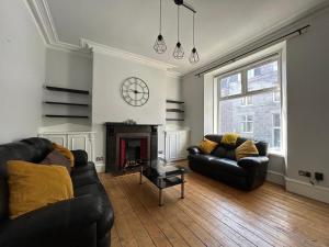 a living room with two leather couches and a fireplace at Howburn Place in Aberdeen