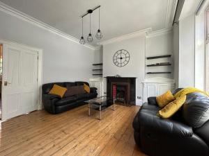 a living room with two leather couches and a fireplace at Howburn Place in Aberdeen
