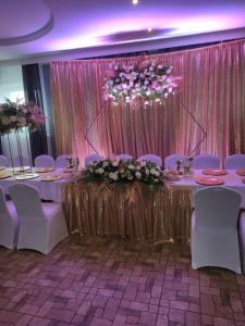 - une salle de banquet avec des chaises blanches et une table fleurie dans l'établissement Carmen, à Głogów