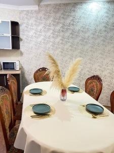 een witte tafel met platen en veren erop bij NURLY TAU APARTMENTS in Alma-Ata