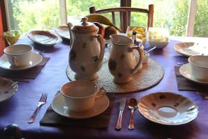 a table with cups and plates and utensils on it at Hotel Rural El Algaire in Arquera de Sales