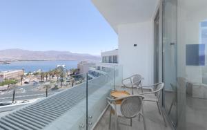 a balcony with two chairs and a view of the ocean at Nathan's Suites On The Beach in Eilat