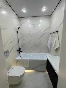 uma casa de banho branca com uma banheira e um WC em 1 комнатная квартира посуточно em Taldykolʼ