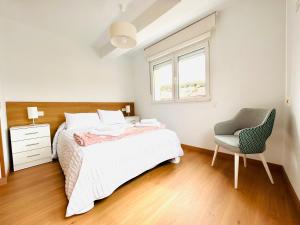 1 dormitorio con 1 cama, 1 silla y 1 ventana en Apartamento San José, en Milladoiro