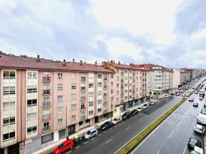 a city street with parked cars and buildings at Apartamento San José in Milladoiro