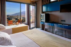 a hotel room with two beds and a tv and a window at Essence Hotel in Ioannina