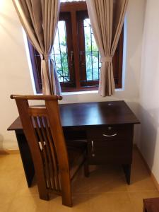 a wooden desk with a chair and a window at Comfortable and serene cottage surrounded with palms and tamarind tree in Rajagiriya