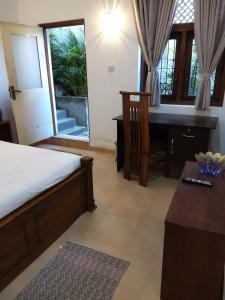 a bedroom with a desk and a bed and a table at Comfortable and serene cottage surrounded with palms and tamarind tree in Rajagiriya