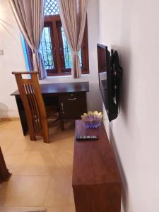 a room with a desk and a table with a bowl of fruit at Comfortable and serene cottage surrounded with palms and tamarind tree in Rajagiriya